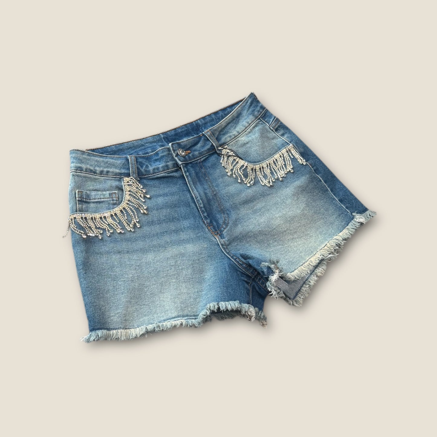 Pantalón corto vaquero con flecos de pedrería en bolsillos