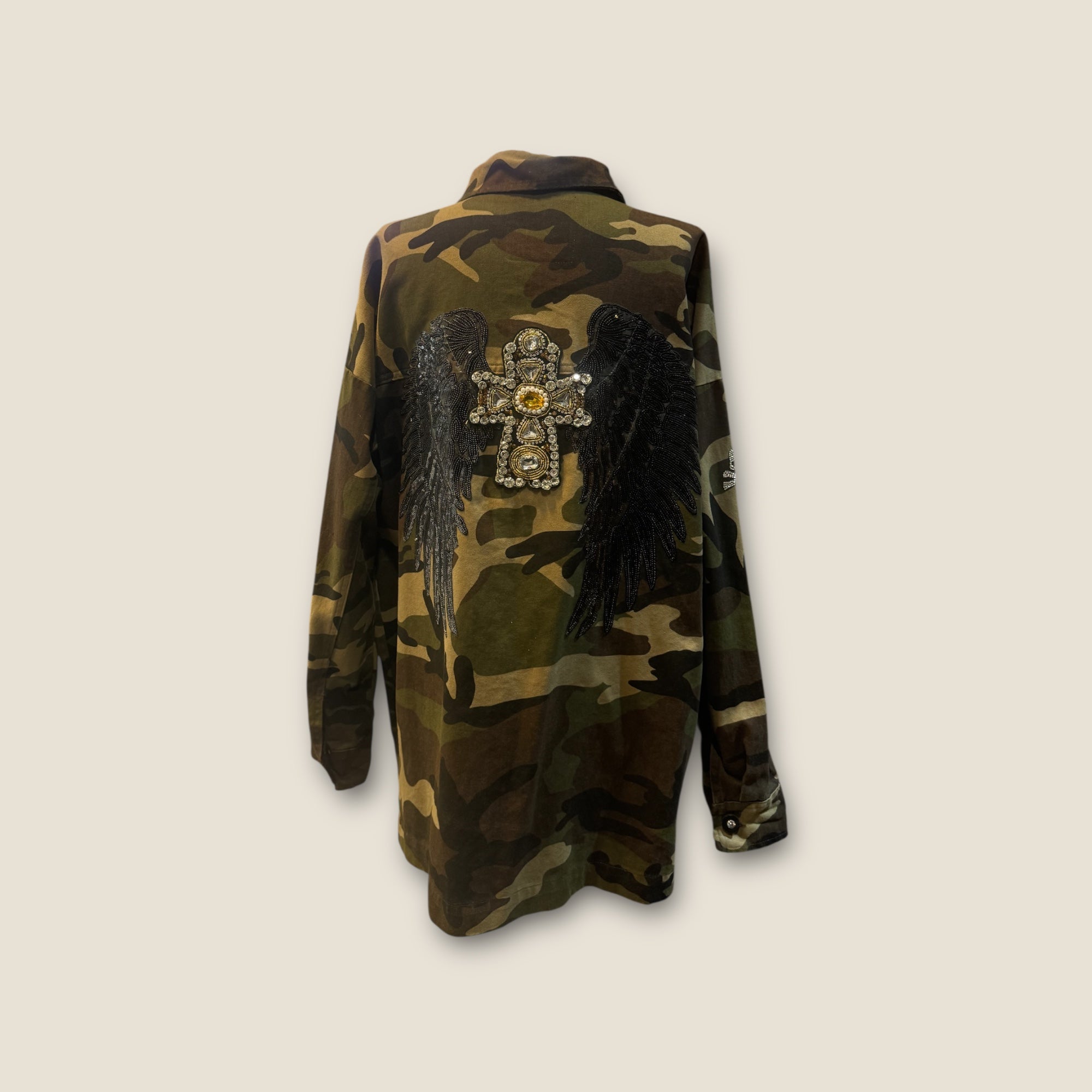 Sobre camisa camuflaje alas negras y cruz de pedrería